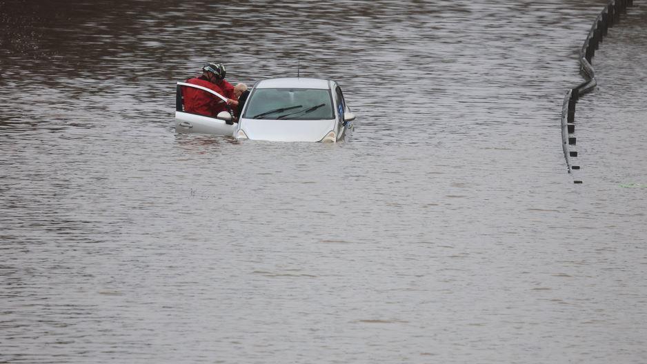 Firefighters rescue a man from his car, after he became trapped in flood water on the A555 near Bramhall