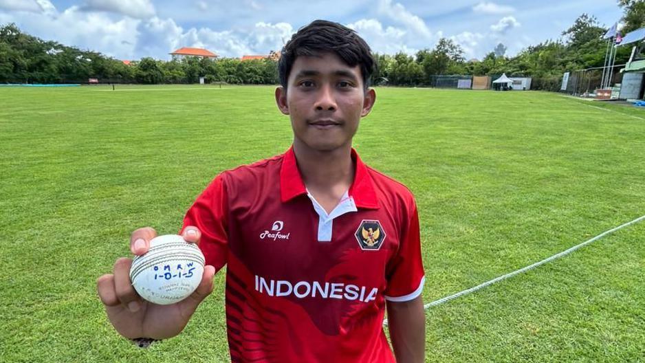 Gede Priandana holding a ball with his bowling figures of 5-1 written on
