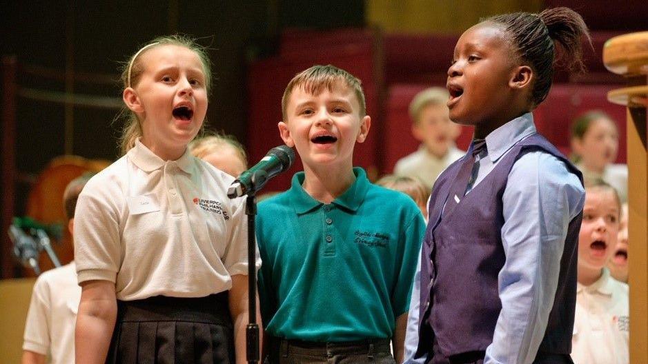 Three children singing into a microphone