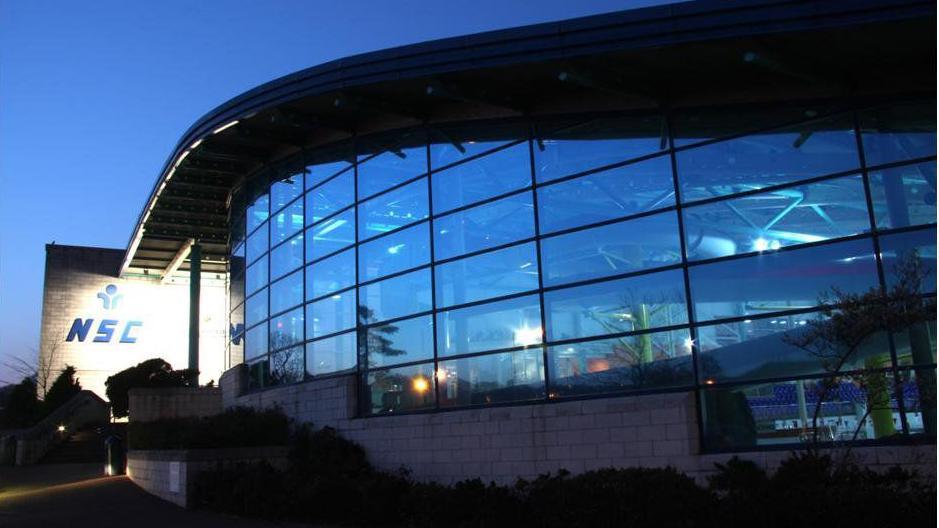 A blue building with a sloped roof and glass frontage