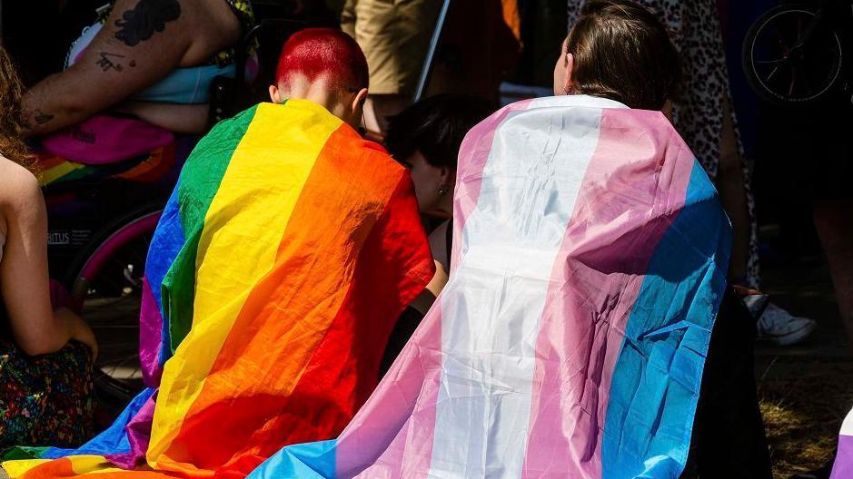 Protesters draped in Rainbow Pride and Transgender flags wait to take part in a London Trans+ Pride march from the Wellington Arch to Soho on 9th July 2022