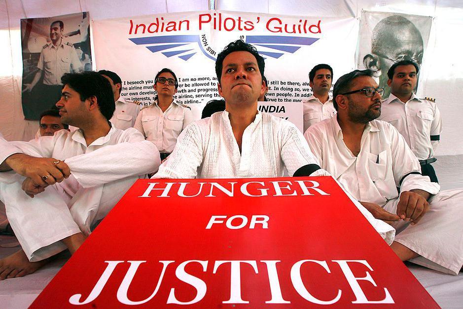 Striking Air India pilots hold placards during a hunger strike in Delhi in 2012