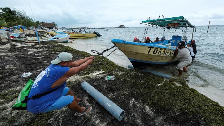 Men pull a boat from the water as Tropical Storm Helene approaches the Yucatan Peninsula, in Cancun, Mexico September 24, 2024.