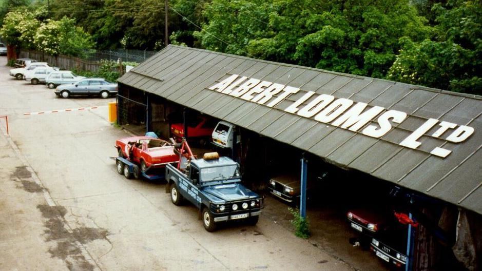 Tow truck parked up next to shed on scrapyard