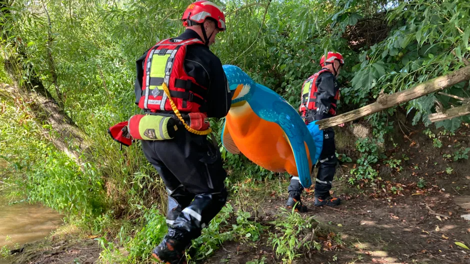 Firefighters carry a penguin sculpture out of the River Severn