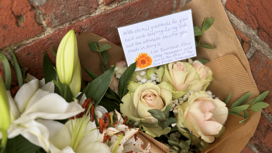 Flowers are laid against a brick wall.