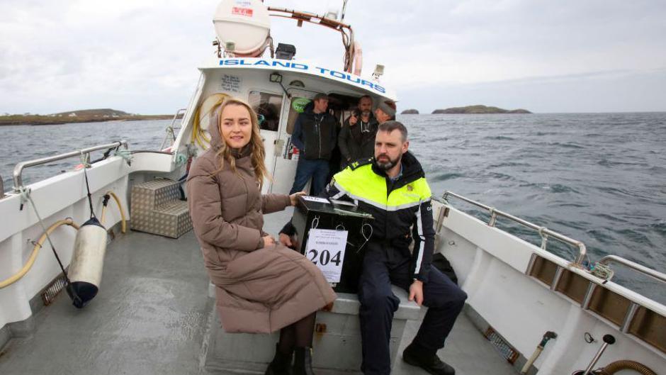 Garda officer and election official pictured at sea on a boat holding ballot box