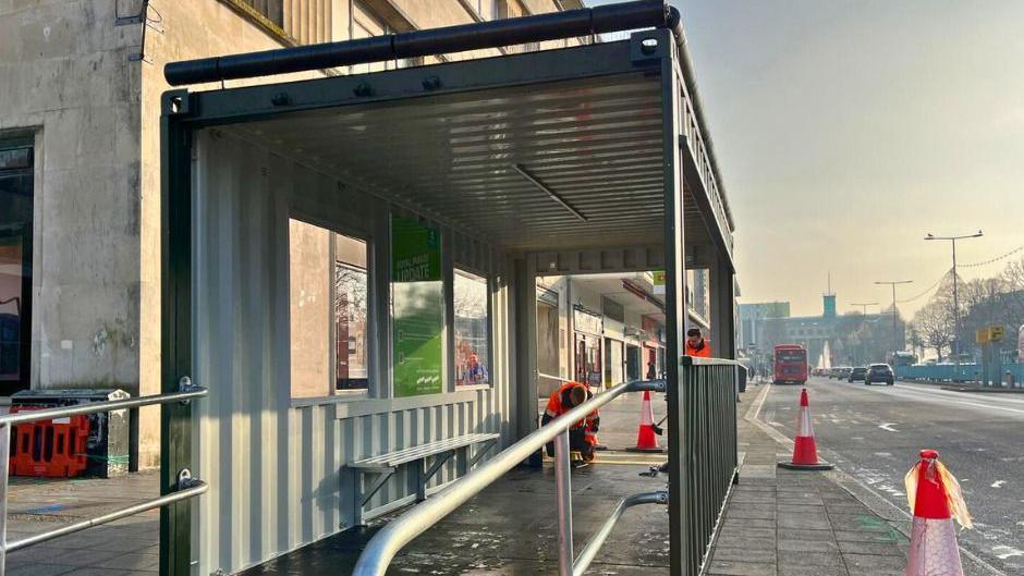 A picture of the temporary bus shelter in place on Royal Parade. It is grey inside with a bench and ramp access.