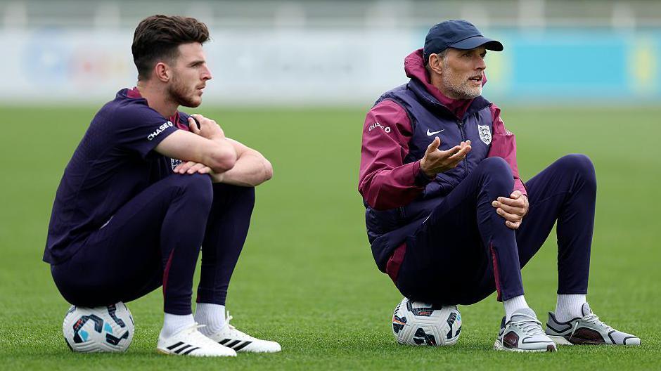 England boss Thomas Tuchel and Declan Rice during a training session sitting on footballs and talking