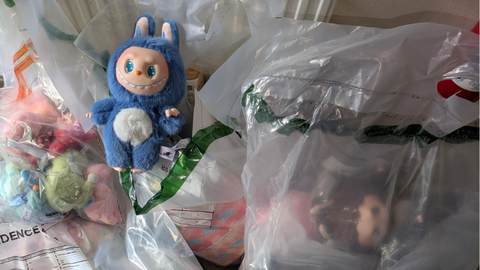 A fake blue Labubu doll, on top of clear bags containing more counterfeit dolls