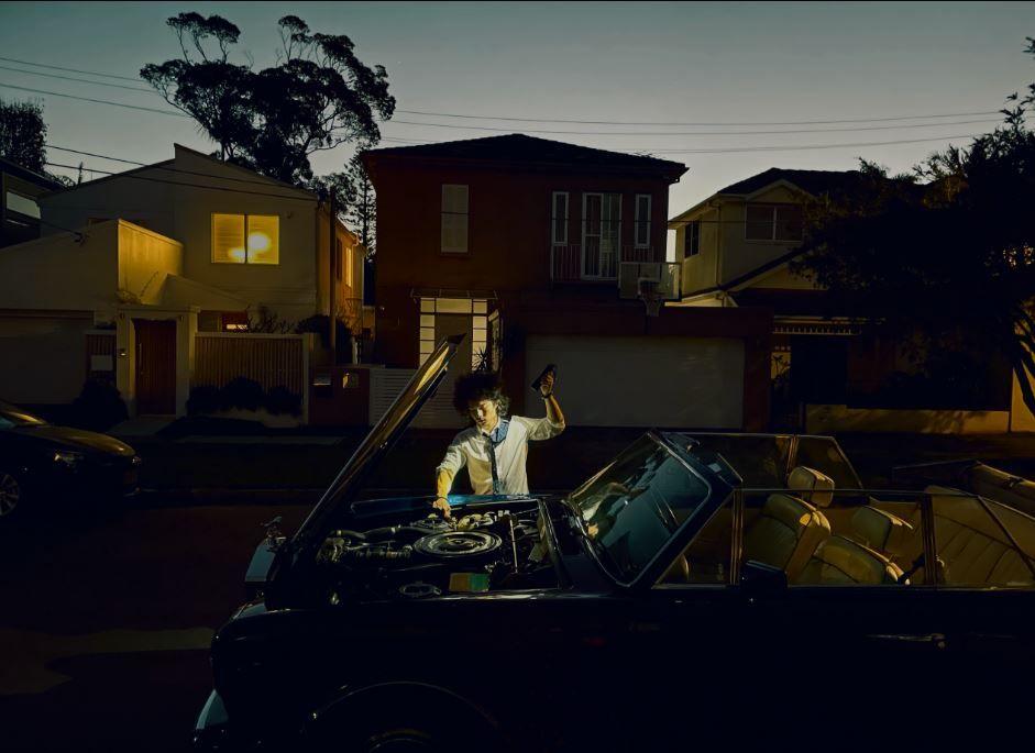 A person fixing their car with their hand in the air. 