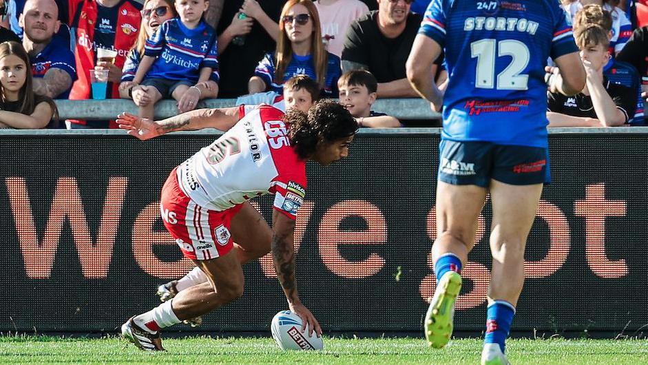 Tristan Sailor dotting the ball down with his right hand to score for St Helens