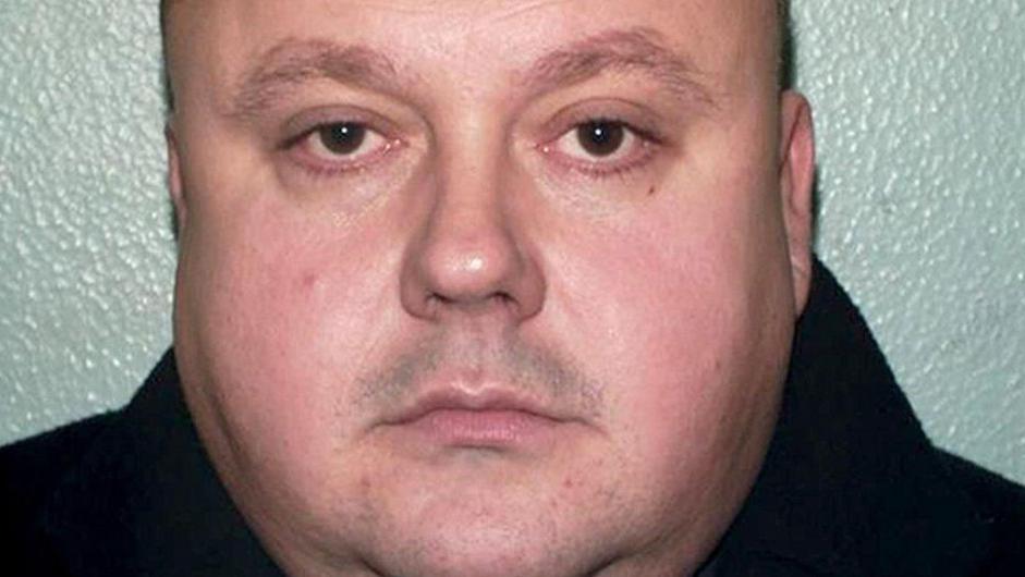 A mugshot of a abdominous  antheral   with stubble connected  his look   wearing a achromatic  hoodie and looking dorectly into the camera with a neutral expression.