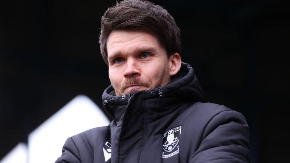 Sheffield Wednesday Danny Rohl, wearing a jacket with the club crest on, watches his team from the touchline