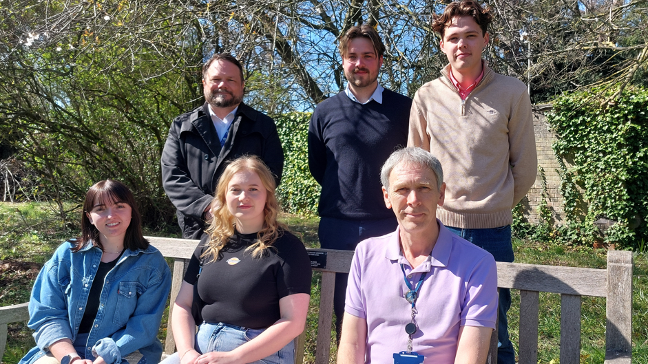 Image of volunteers from the University of Leicester sat on a bench in the sunshine