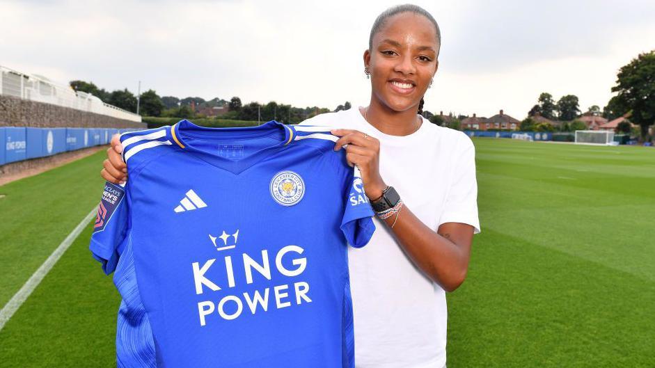 Shana Chossenotte holding up her Leicester shirt