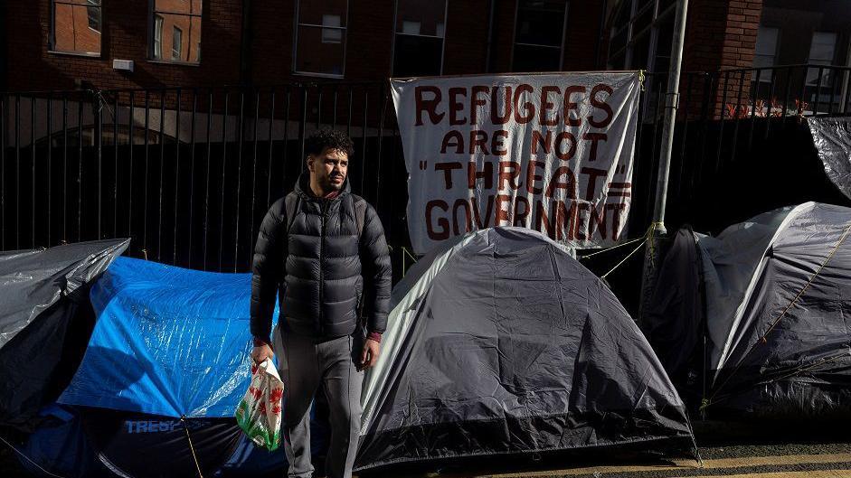  Description An Algerian homeless asylum seeker named Walim walks beside tents outside the International Protection Office (IPO) where hundreds of asylum seekers looking for accommodation have been sleeping on the streets for several months with more arriving every day, in Dublin, Ireland, March 14, 2024. REUTERS/Clodagh Kilcoyne TPX IMAGES OF THE DAY