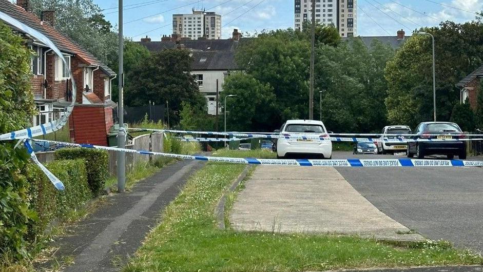 Police tape outside a house, cordoning off a pavement.