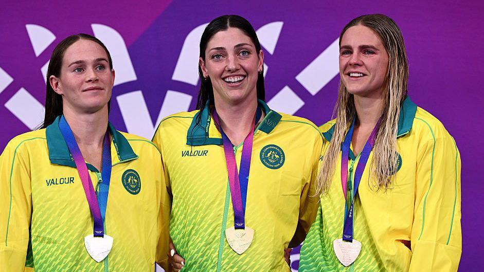 Meg Harris (centre) with two Australia team-mates pose for a photograph after collecting their medals at a swimming medal ceremony