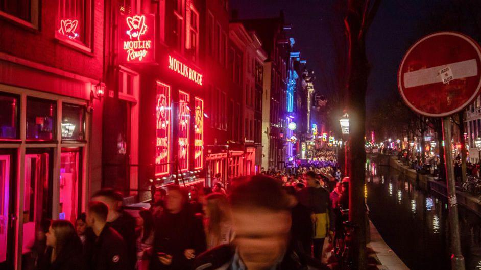 Tourists along the Oudezijds Achterburgwal canal in the red light district in Amsterdam, Netherlands