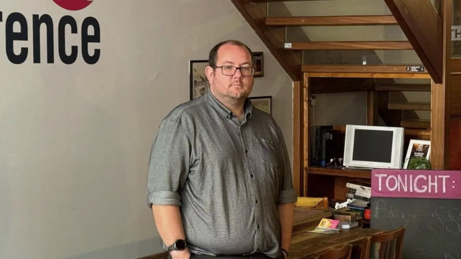 A man in a grey t-shirt and glasses