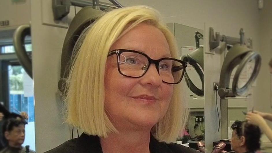 Jackie Grubb looking to the right wearing glasses with a blonde bob, smiling.