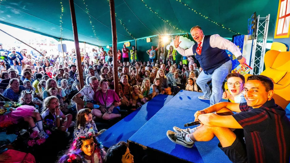 Crowds of adults and children gather in a tent at the festival to see Mr Tumble appear