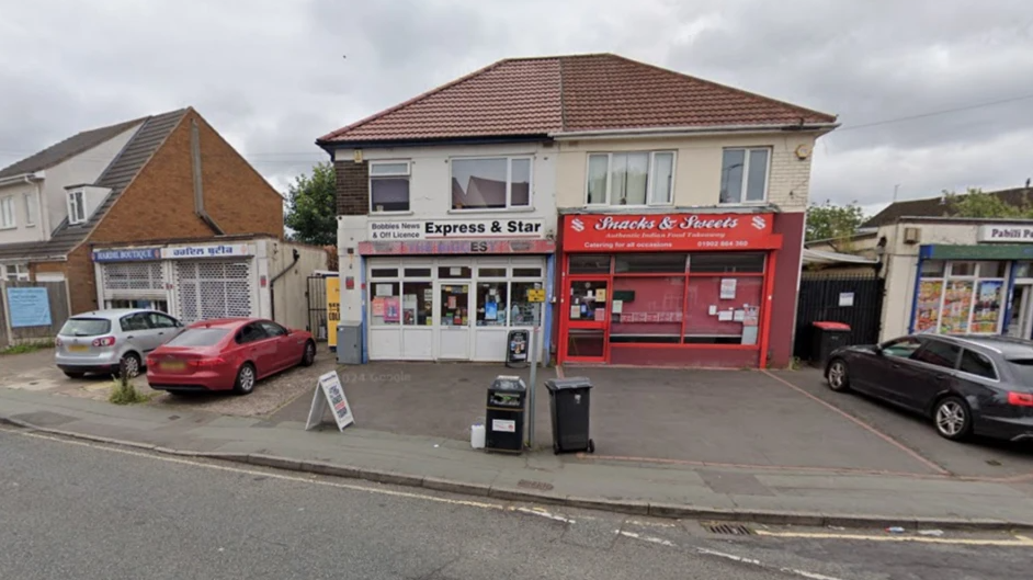The shop is joined to another building which is also a business. The store has a white sign with Express and Star above the door. The building is white with windows and has room for parking in front of it.