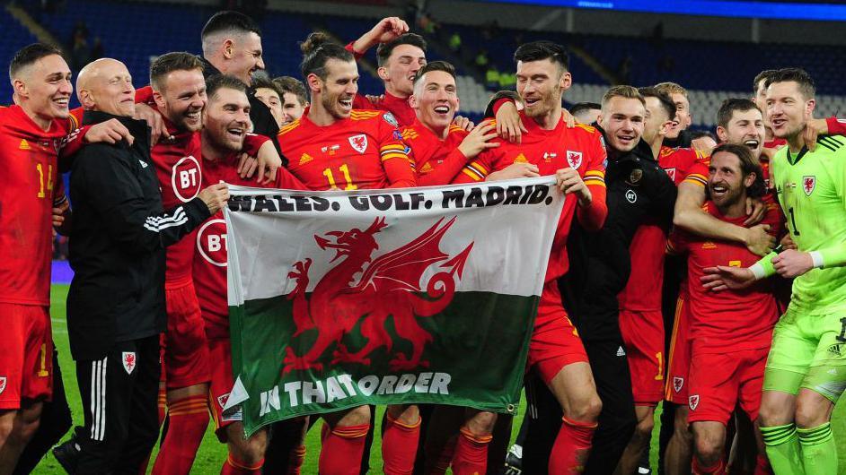 Gareth Bale and Wales team-mates with the 'Wales. Golf. Madrid.' flag after they beat Hungary to qualify for Euro 2020