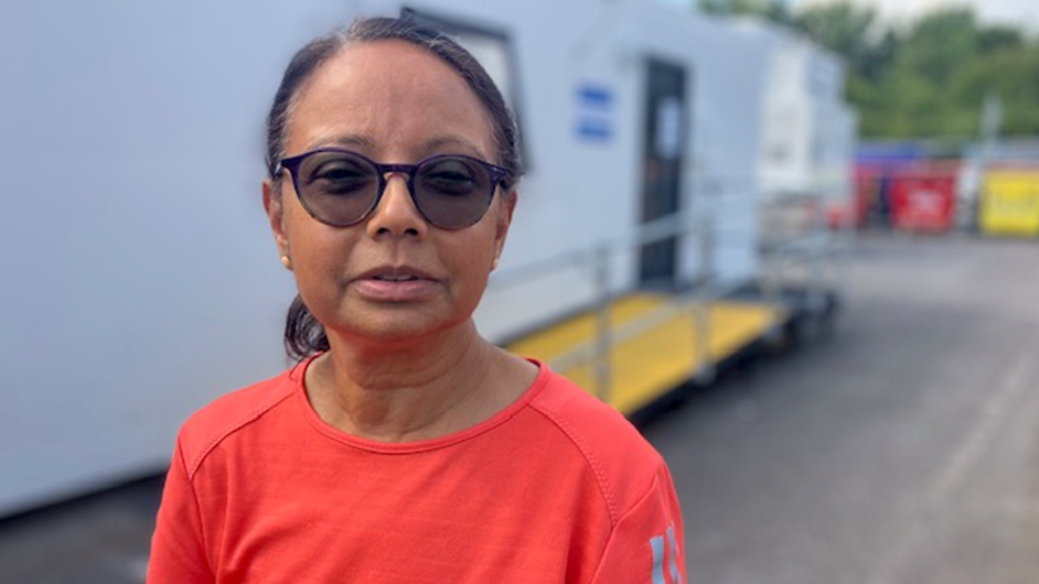 Kiran Mistry in an orange top in front of a white mobile scanning unit