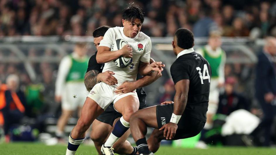 Marcus Smith is tackled during England's narrow defeat by New Zealand at Eden Park in July