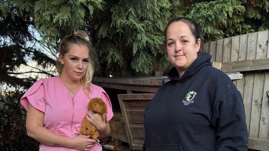 Two women, one holding a guinea pig