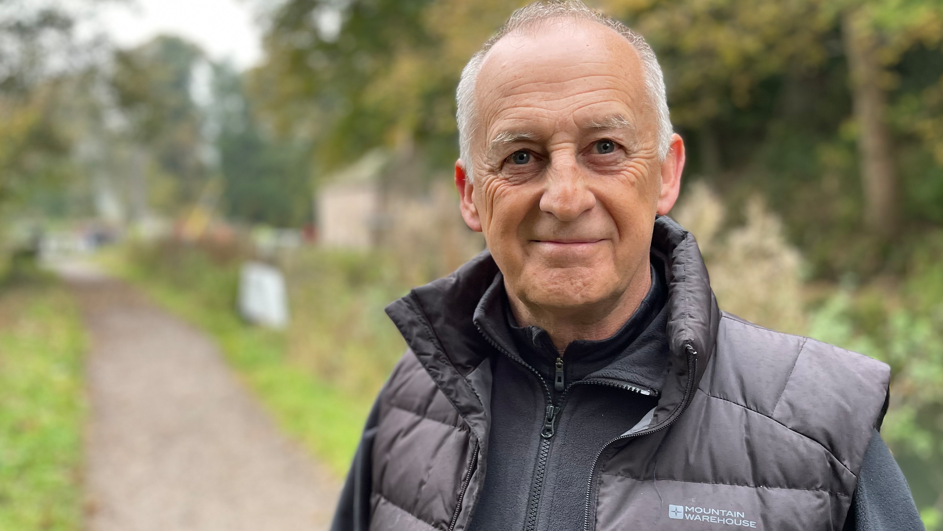 Ron Common standing near the cottage in padded jacket