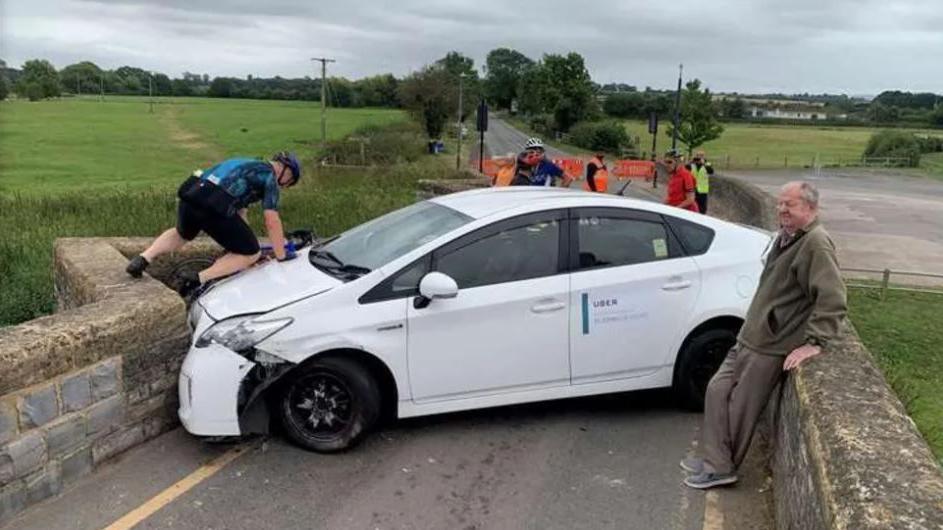 A white Uber car wedged on a 15th Century bridge on the B4085 Honeybourne Road, Bidford-on-Avon