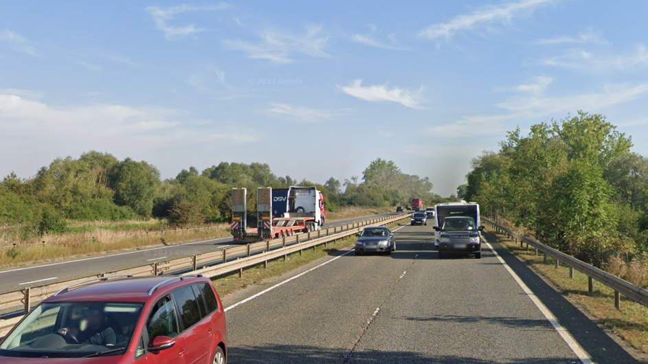 A dual carriageway with a black range rover towing a white caravan and a brown car coming up to overtake. 