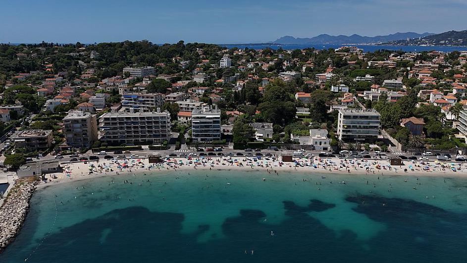 aerial view of a beach with a turquoise sea and some buildings in the background