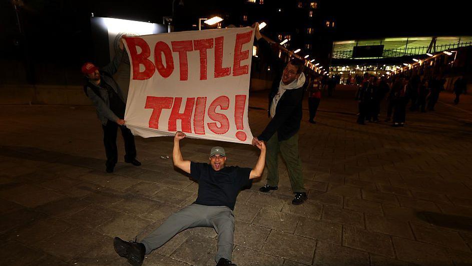 Los aficionados del Arsenal sostienen una bandera que dice "Bottle this" (Embóltala).