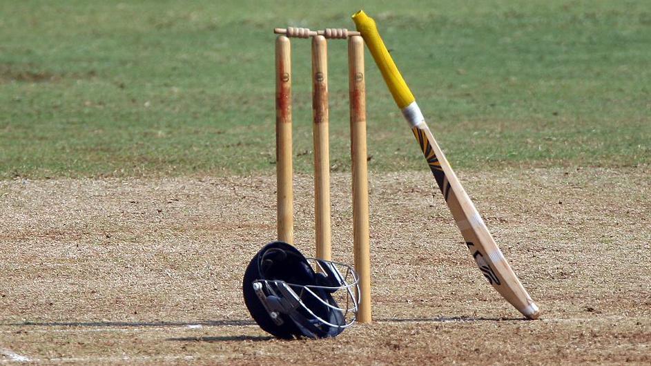 A cricket bat, helmet and stumps.