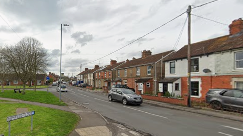 A Google street view of Oldfield Road with houses running along one side and small areas of grass on the other. Two cars can be seen, each going in different directions