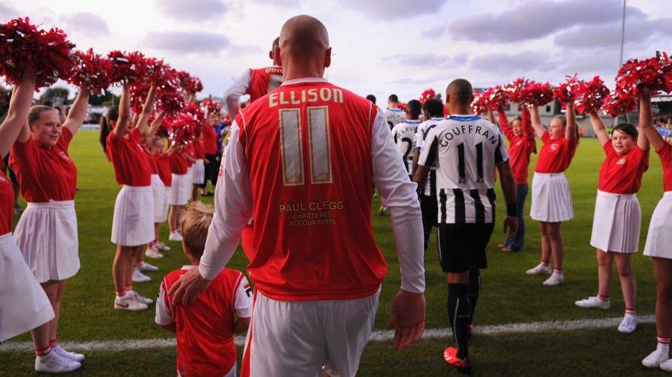 Morecambe's Kevin Ellison, with his back to the camera, walks out before a home League Cup tie with Newcastle United in 2013