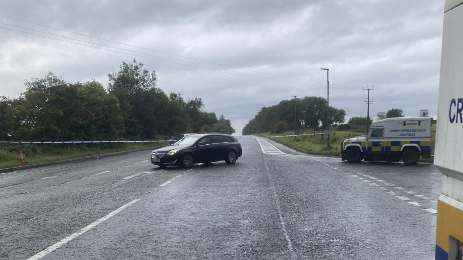 A road cordoned off with police vehicles nearby