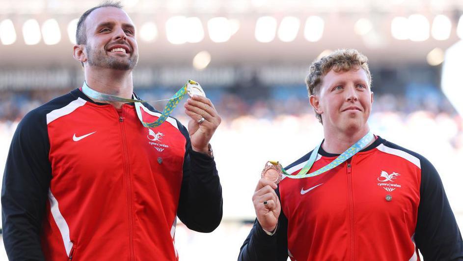 Aled Sion Davies (left) holds his gold medal aloft at the 2022 Commonwealth Games, standing alongside Wales' bronze medal winner Harrison Walsh.