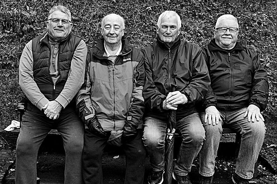 Pedwar dyn yn eistedd ar fainc