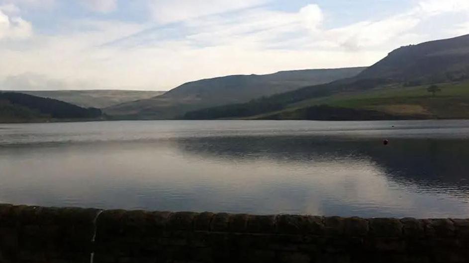 Dovestone Reservoir showing the reservoir with mountains and hills in the background on a clear day.