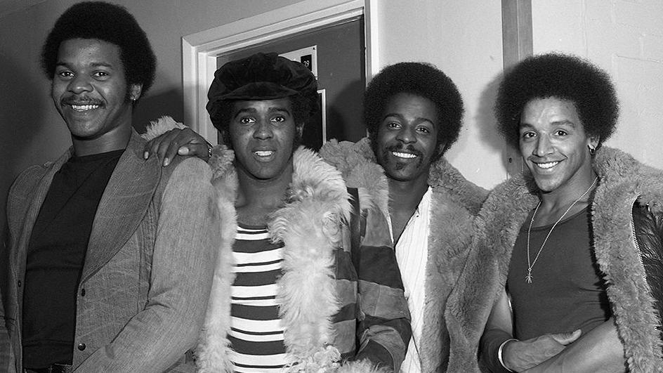 The Real Thing band with all four members of the group smiling standing side by side in an undated image estimated to have been taken in about 1976-77