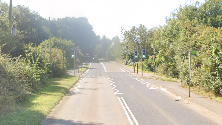 A Google Maps picture of the A3056 between Arreton and Horringford, looking south towards Horringford. The road is empty apart from a car a long way away and a pedestrian crossing is close by.