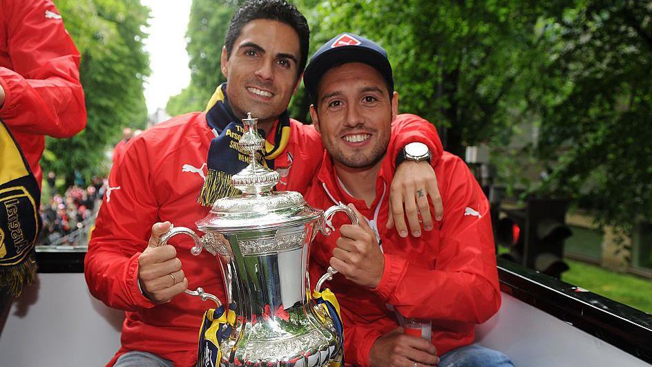 Santi Cazorla and Mikel Arteta are pictured together holding the FA Cup trophy during Arsenal's victory parade in 2015