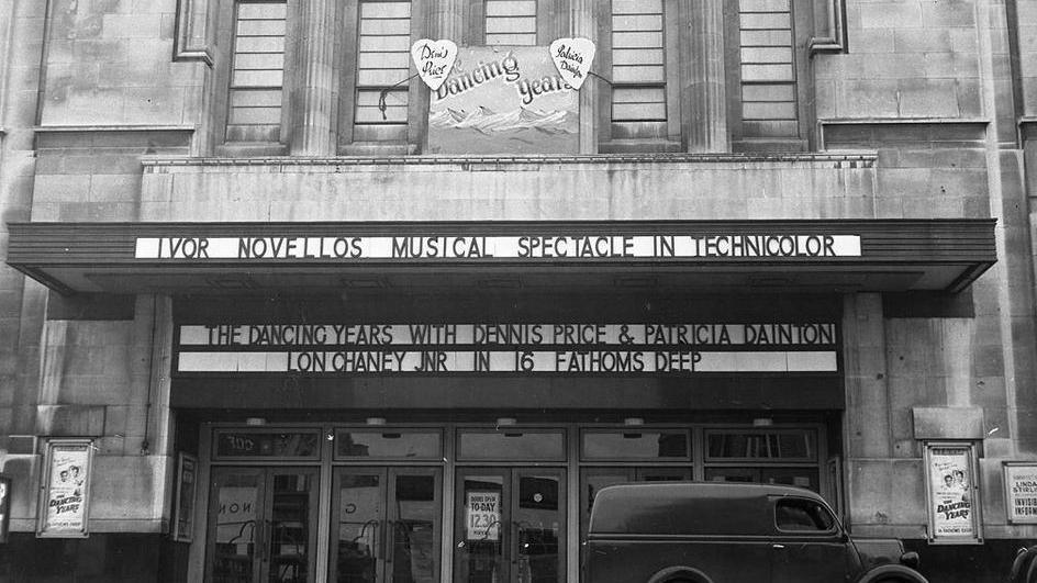 The picture shows the ABC Royal cinema, a vintage movie theatre with a classic architectural style featuring four large columns. Prominently displayed are:
A banner advertising "Ivor Novello's Musical Spectacle in Technicolor"
A marquee listing two films:
"The Dancing Years" starring Dennis Price and Patricia Dainton
"16 Fathoms Deep" featuring Lon Chaney Jr.