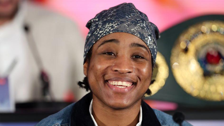 Cindy Ngamba smiles wearing a bandana at a news conference