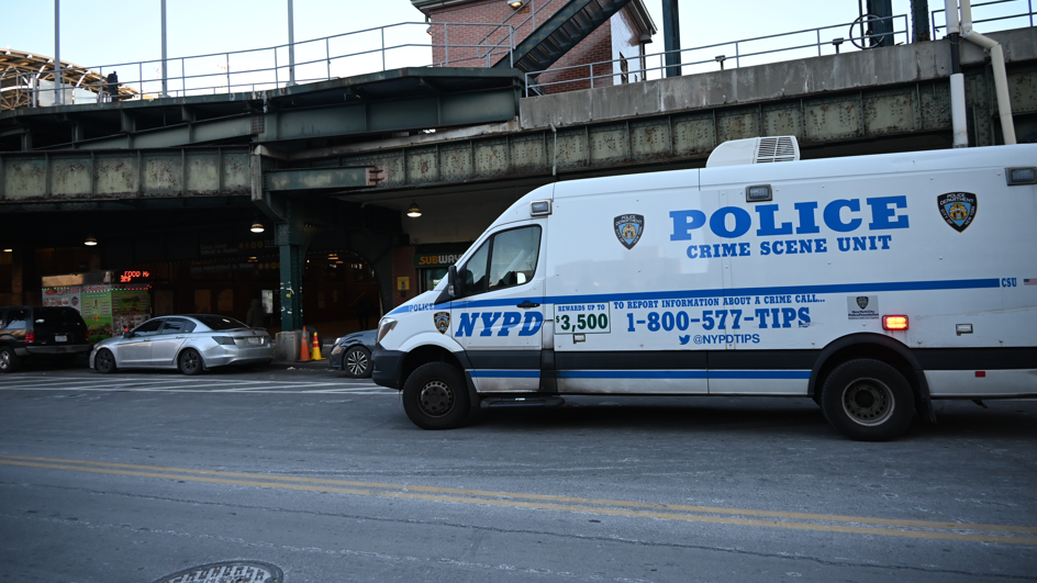 A white NYPD van is parked outside a Brooklyn station where a woman died after being set on fire